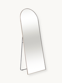 Arched full-length standing mirror with slim taupe aluminium frame and black metal easel back stand, angled three-quarter…