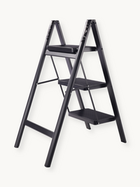 Black metal 3-step folding ladder shown open at angle, with ribbed anti-slip steps and slim A-frame profile
