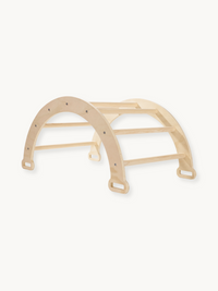 Natural birch wood climbing arch with horizontal rungs and rectangular handle cutouts at base, angled view on white backgr…