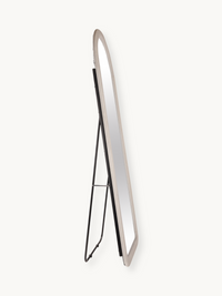 Angled side view of white suede velvet arched floor mirror showing slim profile and black metal A-frame stand on plain bac…