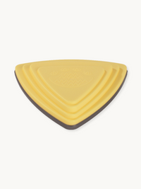 Yellow triangular balance stone, close-up top-down view showing concentric ridges, embossed grip pattern, and dark grey ru…