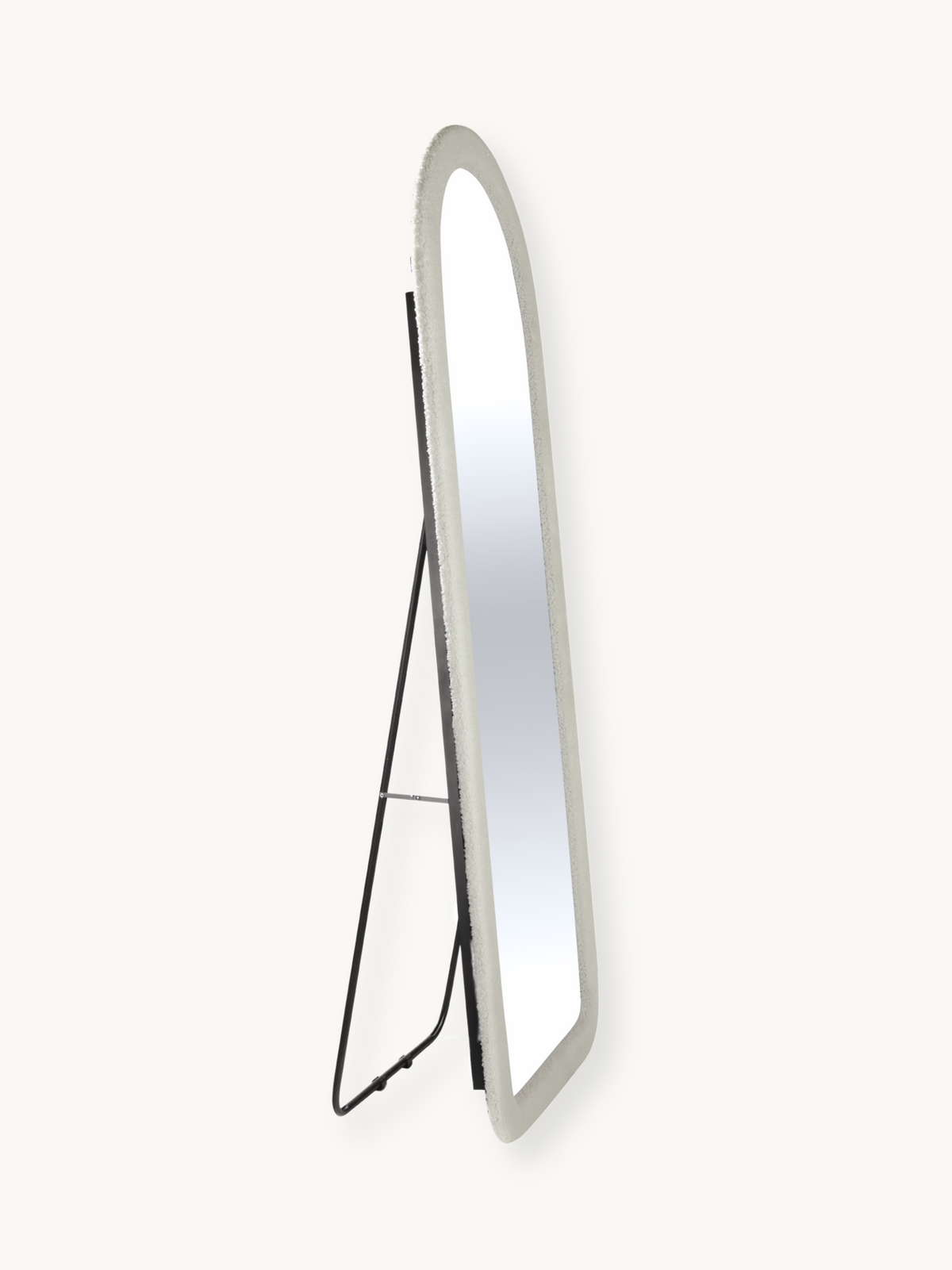 Angled side view of full-length oval mirror with white teddy fabric frame and black metal easel stand, on plain background
