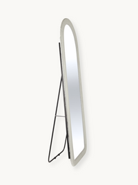 Angled side view of full-length oval mirror with white teddy fabric frame and black metal easel stand, on plain background