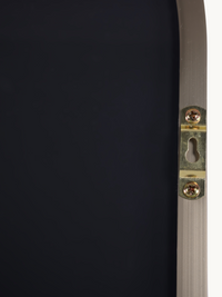 Close-up of gold-tone keyhole wall-mounting bracket screwed onto the back of a taupe brushed aluminium mirror frame