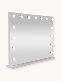 White Hollywood vanity mirror with 15 LED bulbs, pale lilac-tinted frame, angled three-quarter view showing depth and base…