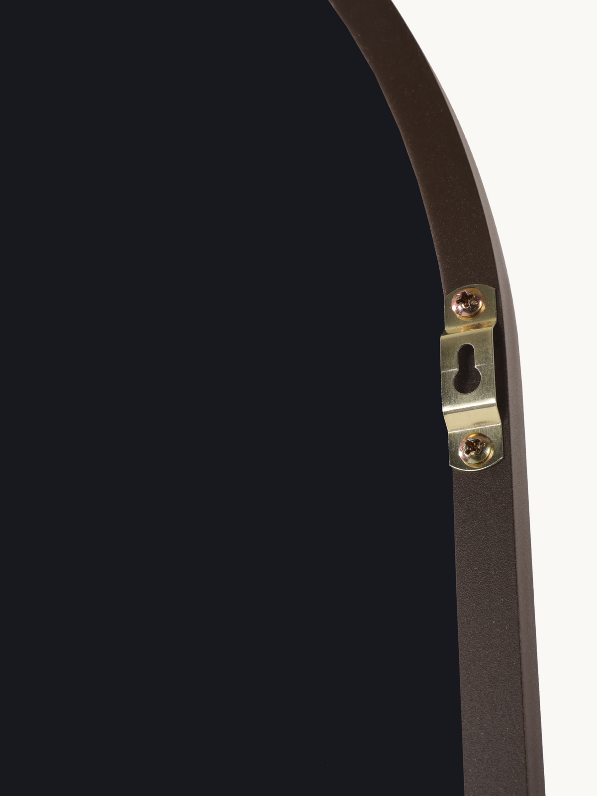 Close-up of brass keyhole wall-mounting bracket screwed onto the back of a brown aluminium oval mirror frame
