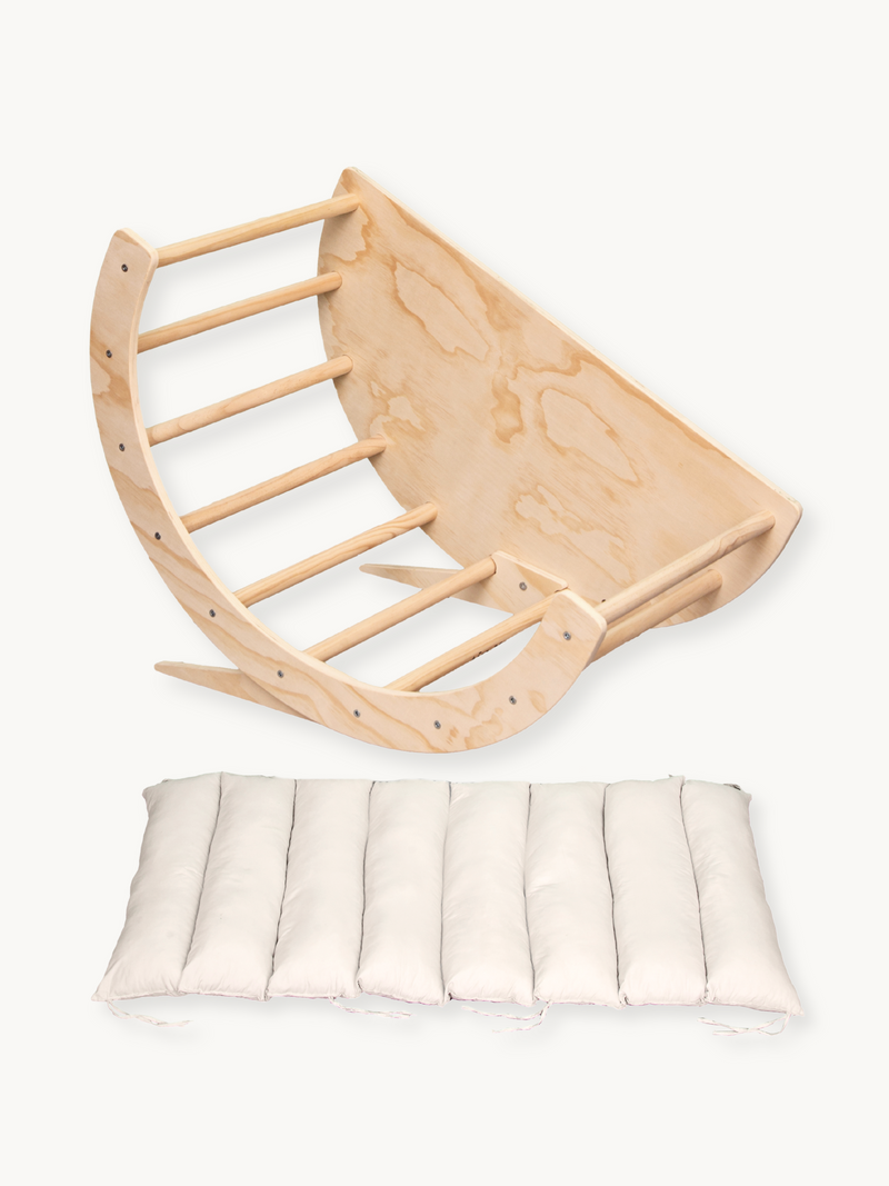 Natural birch wood climbing arch and rocker shown overhead, with detached cream segmented cushion below