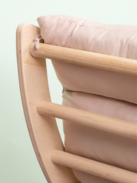 Close-up of natural wood horizontal rungs and curved side frame with blush pink cushion ties securing the fabric in place