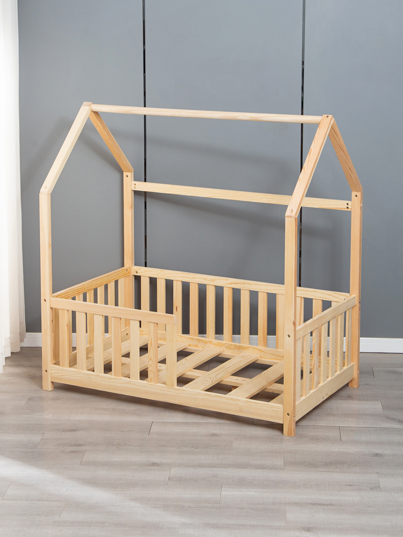 Natural pine toddler house bed without mattress, showing slatted base and three-sided safety rails, angled view against gr…