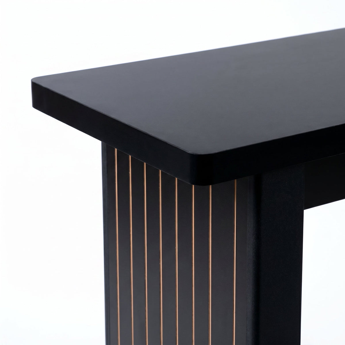 Close-up of black console table corner showing smooth gloss top edge and ribbed leg with thin gold-toned wood grain lines