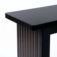 Close-up of black console table corner showing smooth gloss top edge and ribbed leg with thin gold-toned wood grain lines