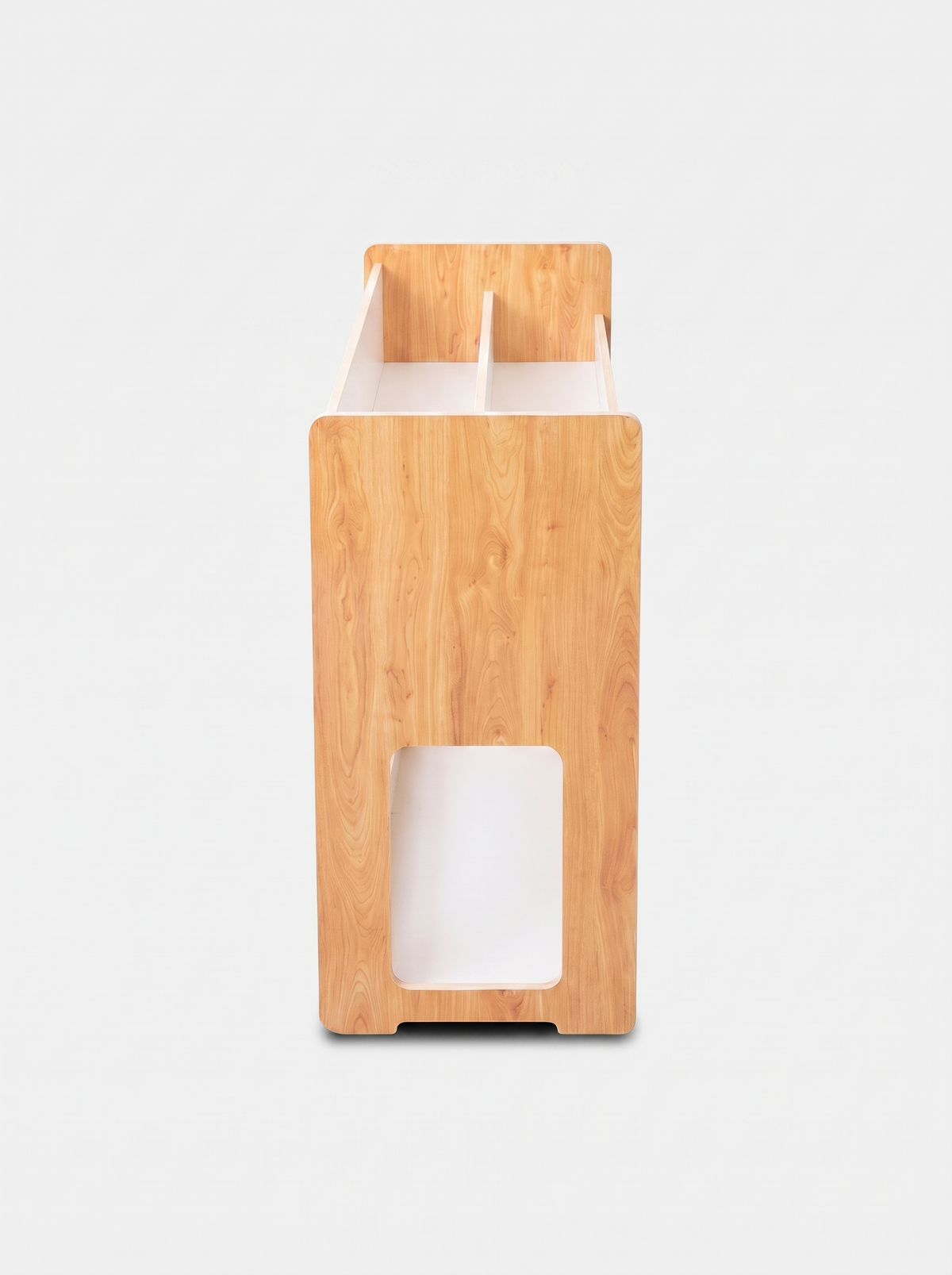 Narrow end-panel view of natural pine kids bookcase showing rounded corners, rectangular cutout, and divided top slots, wh…