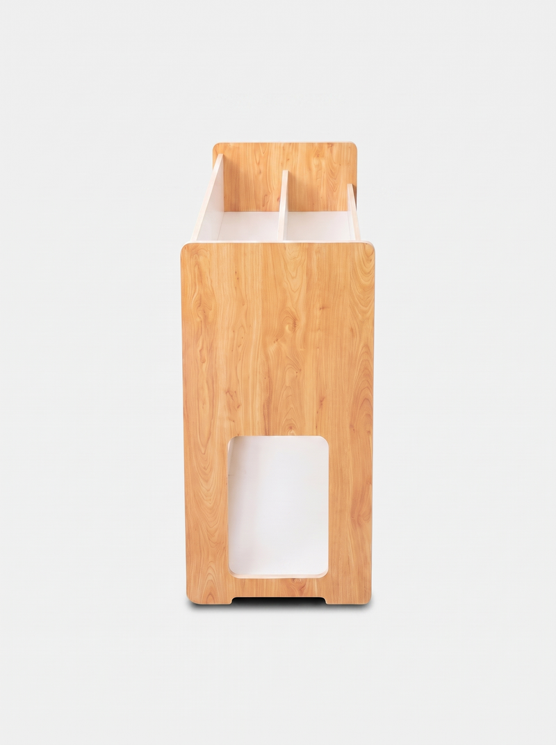 Narrow end-panel view of natural pine kids bookcase showing rounded corners, rectangular cutout, and divided top slots, wh…