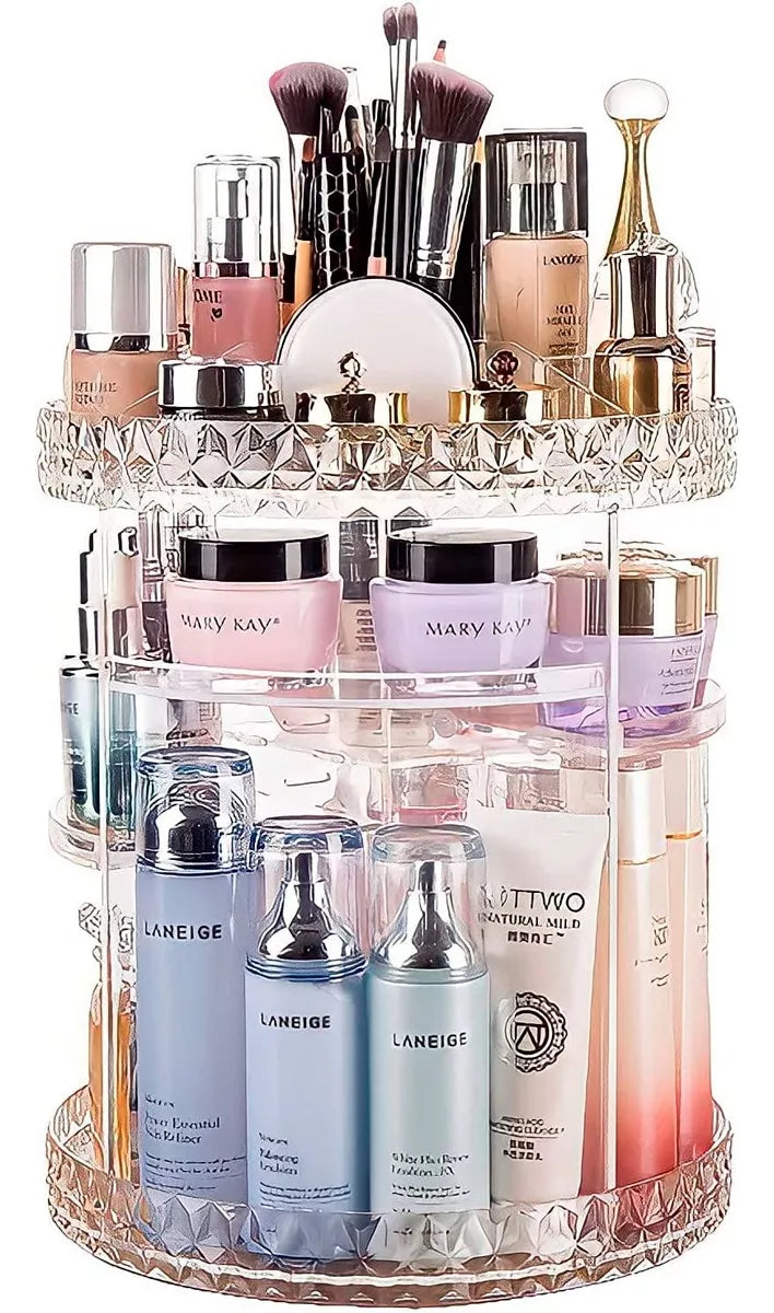 Clear 3-tier rotating makeup organiser filled with skincare bottles, makeup brushes, creams and perfumes on white background