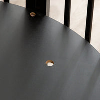 Close-up of matte black round tabletop surface showing central umbrella hole and a visible screw fixing, black spindle leg…