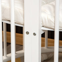 Close-up of white wooden cot frame joints secured with two bolts, cream quilted mattress visible between vertical slats