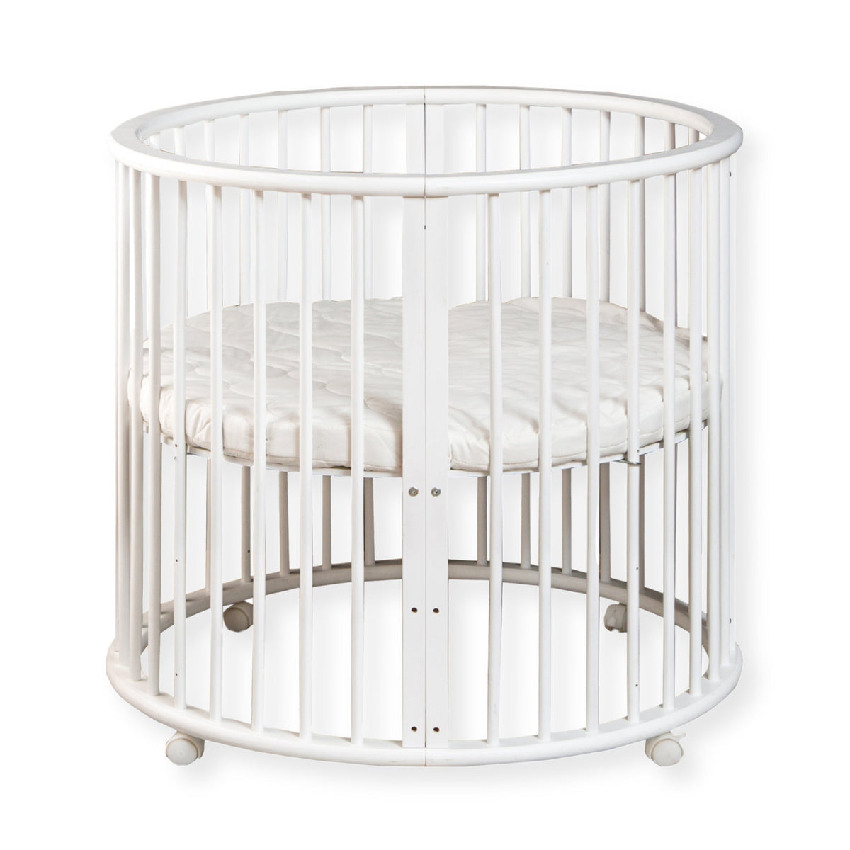 White round wooden baby playpen with vertical slats, circular mattress inside, and four castors, front view on white backg…