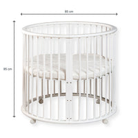 White round wooden baby playpen with dimension arrows showing 85 cm width and 85 cm height, cream mattress inside, white b…